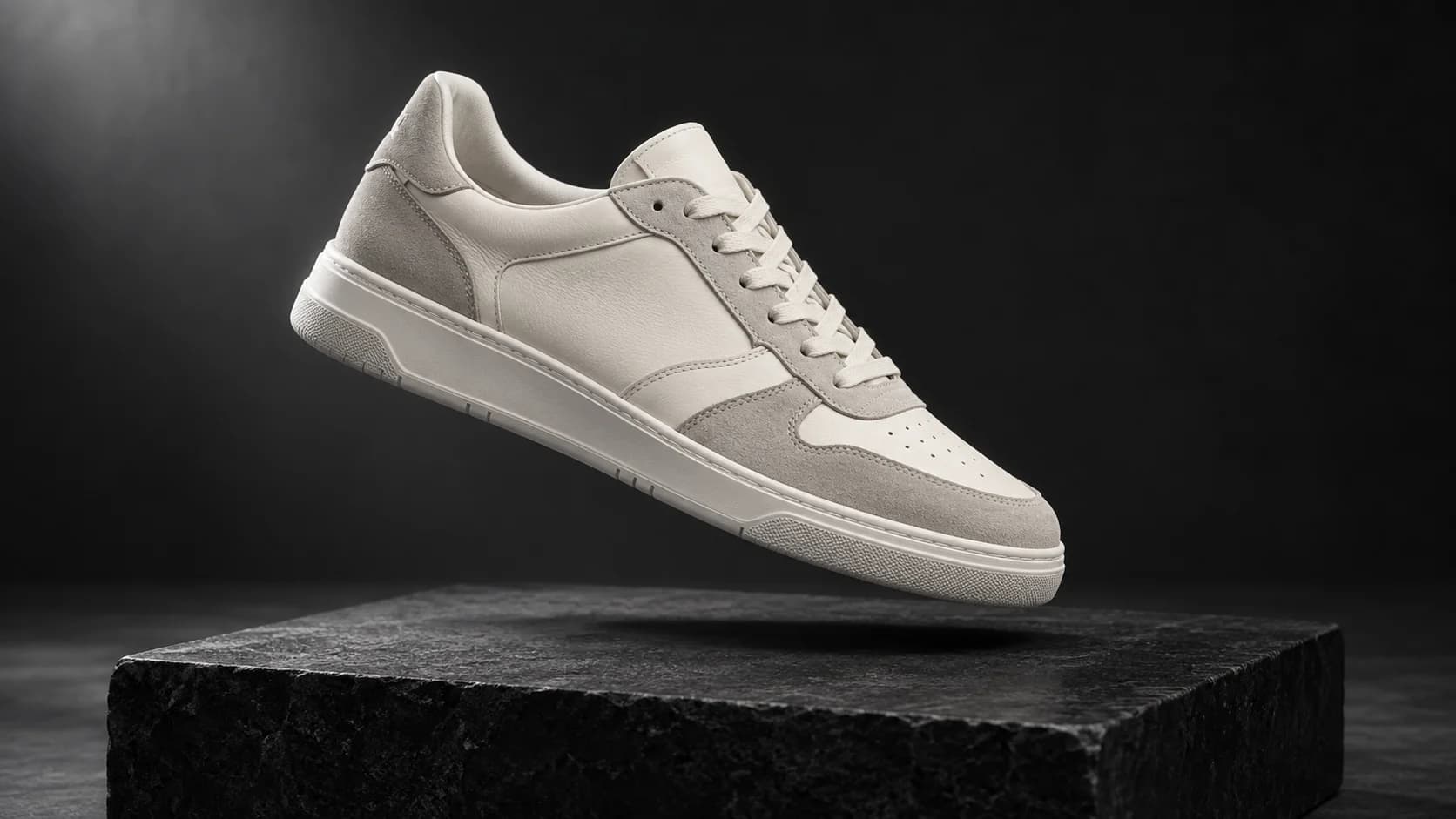 Off-white sneaker suspended above a charcoal pedestal in a product campaign photograph